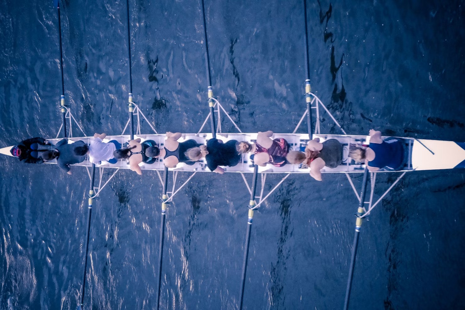 Rowing crew seen from above, moving together on dark water