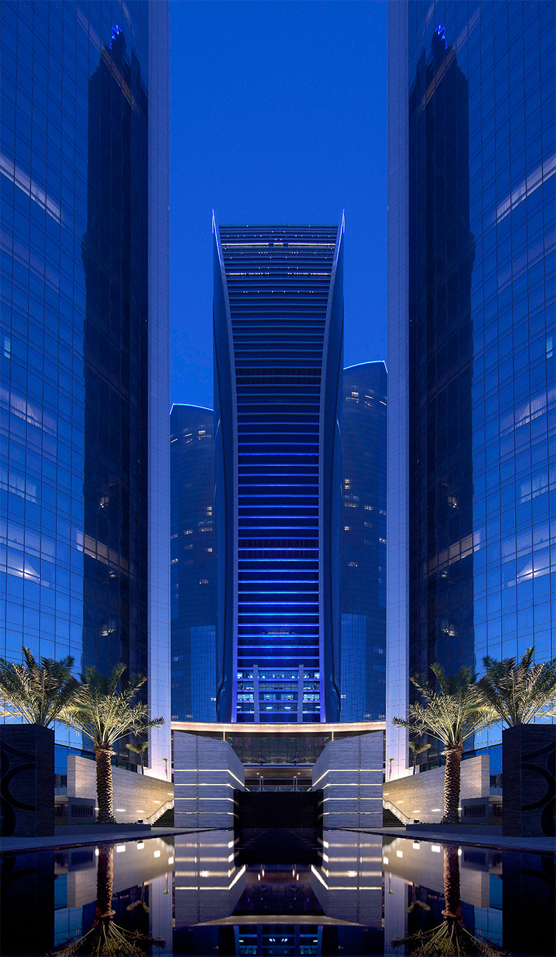 Symmetrical glass towers at dusk reflected in a still pool